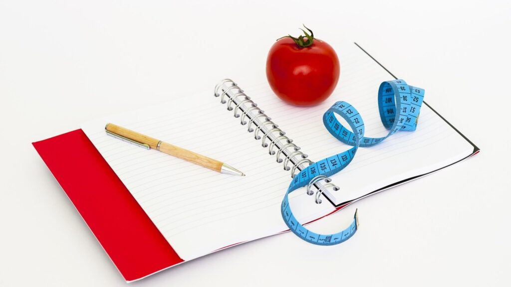 Notizblock mit Maßband, Stift und Tomate